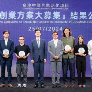 Nine people assembled on stage. Seven are holding awards