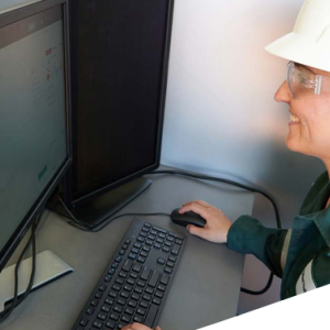A person in protective gear working on a desktop computer.