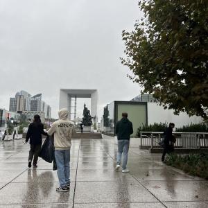People walking outside on a rainy day, some collecting trash.