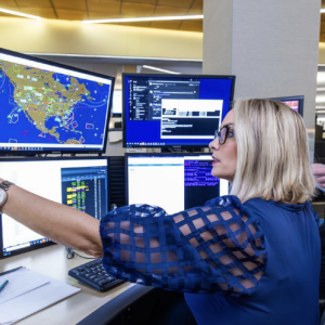 Two people looking at multiple computer monitors 