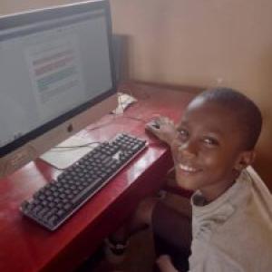A smiling child using a computer.