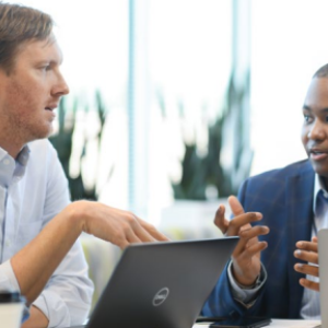 Two people talking while on laptops