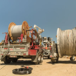 a worker in safety gear and large coils of cable