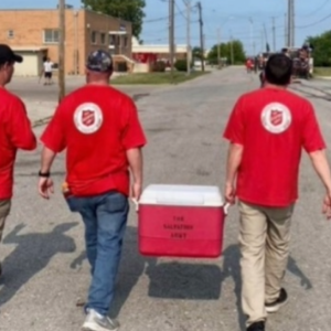 Three volunteers walking away, two carrying a cooler.