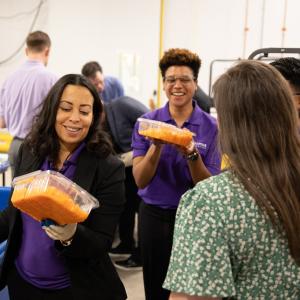 Smiling people holding clear containers.