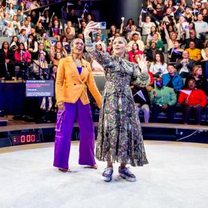 Two people taking a selfie at an event with the audience 