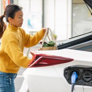 person putting groceries into a charging car