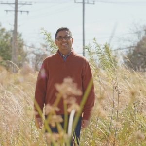 A smiling person standing in a field of cover-crop