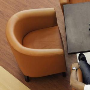 Two people seated in armchairs, a laptop open on a small table in front of them.