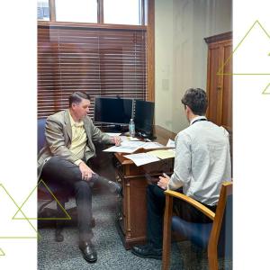 Two seated people looking at papers on a desk