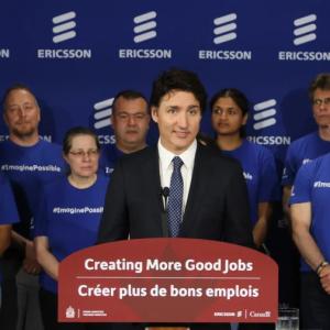 Canadian Prime Minister Justin Trudeau speaking at a podium, a small group of people behind him.