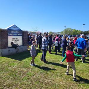 A large group standing by a sign for the school.