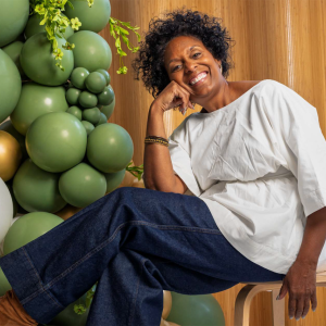 Person sitting on a chair next to green balloons