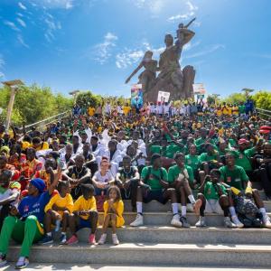 A large group of people outside, sitting on steps leading up to a monument