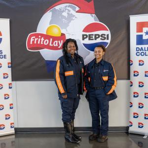 Two people posed by Dallas College banners