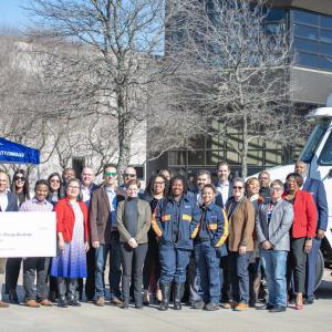 A group of people posed outside in front of a semi truck