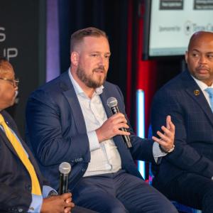 Three people with microphones seated on a stage