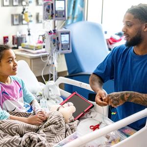 Damar Hamlin talking with a child in a hospital bed.