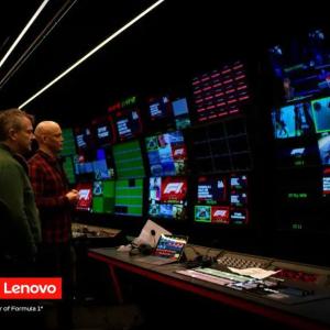 Two people in a dim room watching multiple monitors.