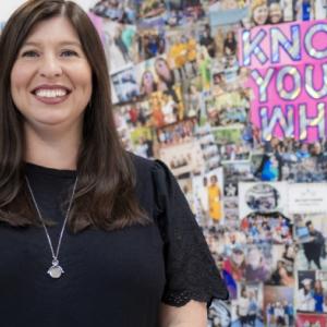 Dawn Martesi In her office, stood in front of a board with photos of students she’s taught in the past
