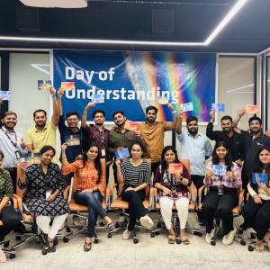 A group posed, each holding up a card. "Day of Understanding" poster behind them.