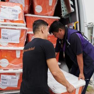 Two people loading containers into the back of a van
