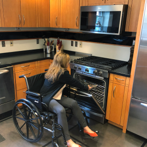 woman in a wheelchair places a glass casserole dish in an oven