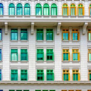 exterior view of rows of rainbow colored window frames on a white building