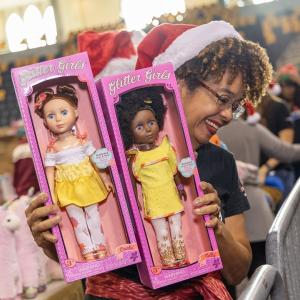 A volunteer holding up two packaged dolls