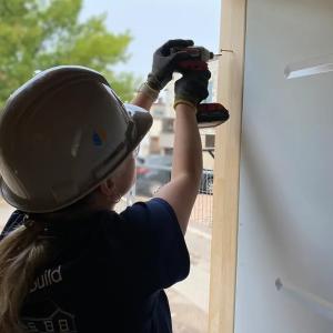 A person using a drill on a door frame.