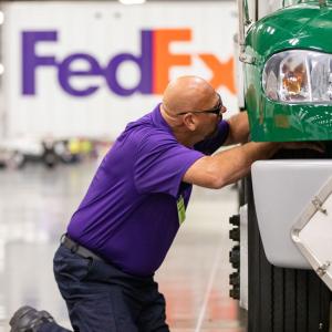 driver in purple shirt inspecting a green truck