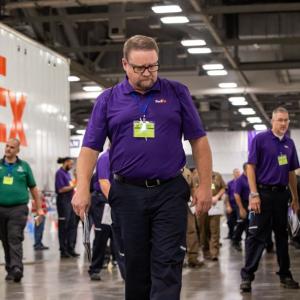 driver in purple shirt and glasses inspects a truck