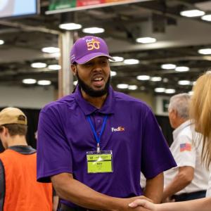 fedex driver in a purple hat shaking the hand of a competition judge