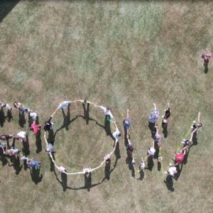 Aerial drone image of people in a field connected to form the word "CROWN".
