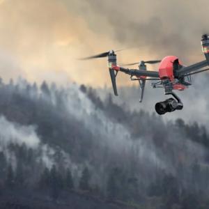 A drone flying over a smoke filled forest.