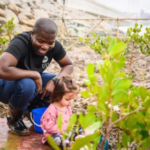 Adult and child sitting at water's edge