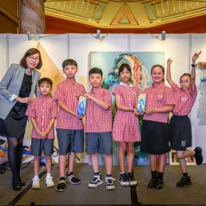 A group of children and an adult posed in front of an exhibit with sea creatures.
