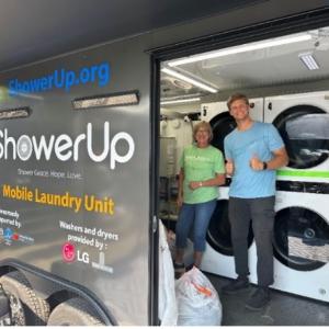Two people smiling inside an open ShowerUp mobile laundry unit