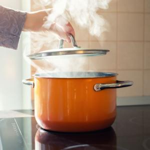 Steam rising from an orange pot on an electric range