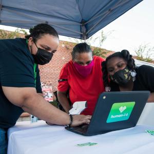 Three people looking at a Human-I-T laptop