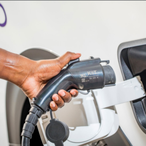 a hand holding a vehicle charge plug near the port on the vehicle