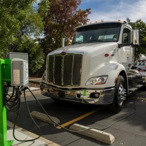 An electric semi-truck parked and plugged into a charging station.