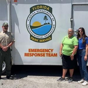 3 people standing in front of emergency response trailer