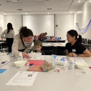 Two adults and a child participating in science experiments and activities