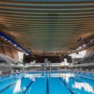 A large enclosed swimming pool with stadium seating on the sides