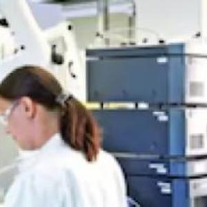 Two people in a lab wearing protective gear.