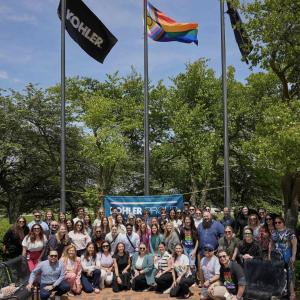 A group posed in front of flags on poles.