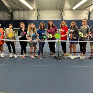 A group of women holding pickle ball paddles