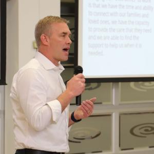 A person with a microphone speaking behind a podium.