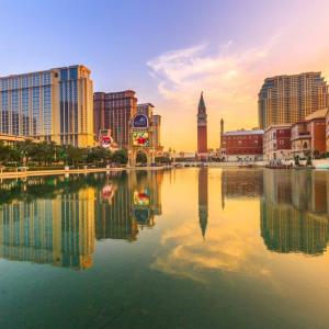 Scenic water view with skyline of tall buildings and sunset in the distance.